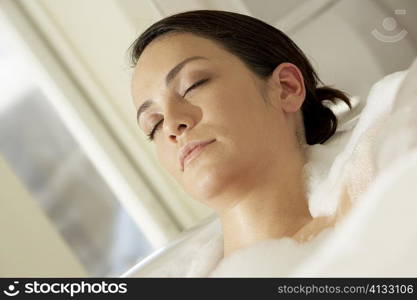 Close-up of a young woman in a bathtub with her eyes closed