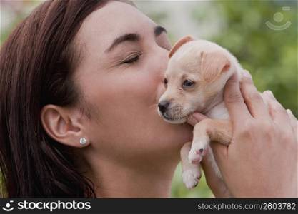 Close-up of a young woman kissing a puppy