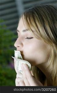 Close-up of a young woman kissing American dollar bills
