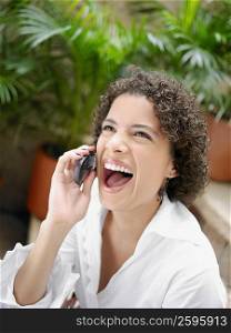 Close-up of a young woman laughing while talking on a mobile phone