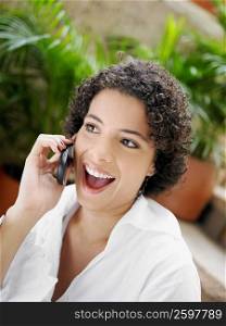 Close-up of a young woman laughing while talking on a mobile phone
