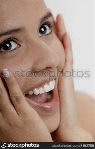 Close-up of a young woman laughing with her hands on her head