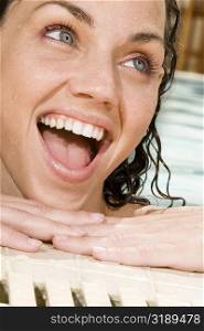 Close-up of a young woman leaning at the edge of a swimming pool and laughing