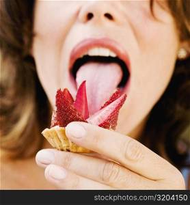 Close-up of a young woman licking a strawberry tart