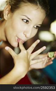 Close-up of a young woman licking her finger