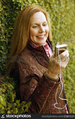 Close-up of a young woman listening to an MP3 player and smiling