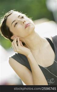 Close-up of a young woman listening to music and looking up