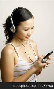 Close-up of a young woman listening to music and operating a mobile phone