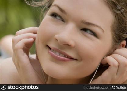 Close-up of a young woman listening to music and smiling
