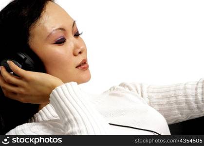 Close-up of a young woman listening to music through headphones
