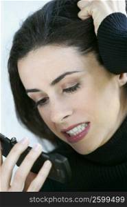 Close-up of a young woman looking angry at a mobile phone