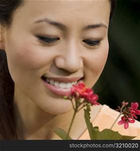 Close-up of a young woman looking at a flower and smiling