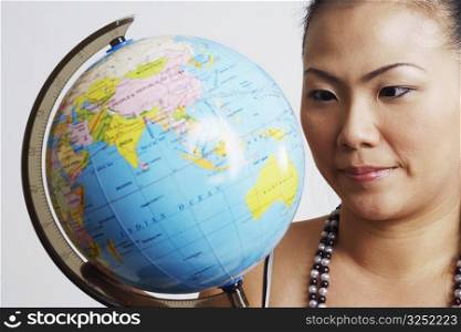 Close-up of a young woman looking at a globe