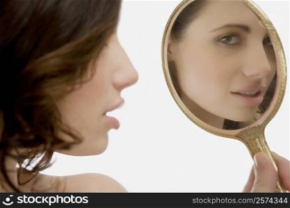 Close-up of a young woman looking at a mirror