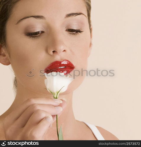 Close-up of a young woman looking at a white rose