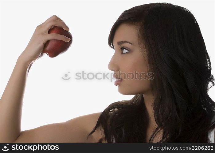 Close-up of a young woman looking at an apple