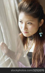 Close-up of a young woman looking out of a window