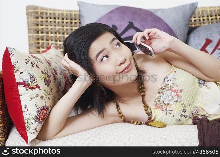 Close-up of a young woman lying on a couch and talking on a mobile phone