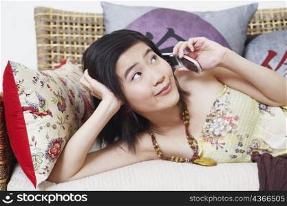 Close-up of a young woman lying on a couch and talking on a mobile phone