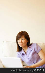 Close-up of a young woman lying on a couch with a laptop