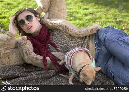 Close-up of a young woman lying on a picnic blanket behind a puppy