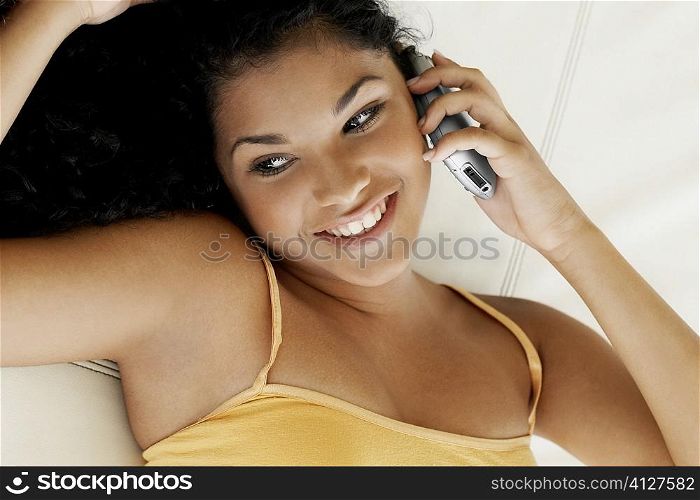 Close-up of a young woman lying on her back and talking on a mobile phone
