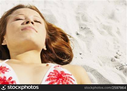 Close-up of a young woman lying on the beach
