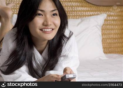 Close-up of a young woman lying on the bed and watching television
