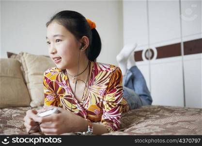 Close-up of a young woman lying on the bed listening to music
