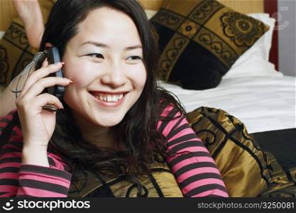 Close-up of a young woman lying on the bed using a mobile phone