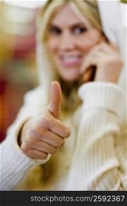 Close-up of a young woman making a thumbs up sign