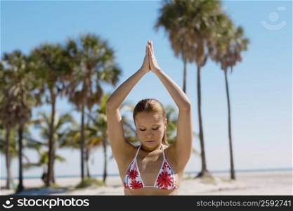 Close-up of a young woman meditating on the beach