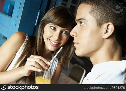 Close-up of a young woman offering a glass of juice to a young man