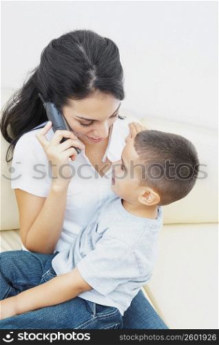 Close-up of a young woman on the phone and her son sitting on her lap