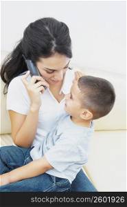 Close-up of a young woman on the phone and her son sitting on her lap