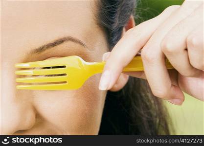 Close-up of a young woman peeking through a fork