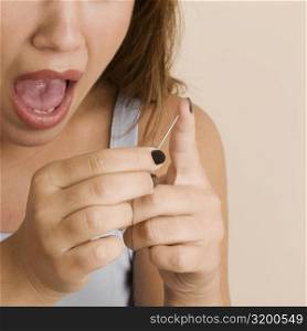 Close-up of a young woman pinching her finger with a needle