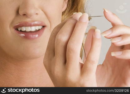 Close-up of a young woman pinching her finger with a needle