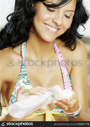 Close-up of a young woman pouring suntan lotion on her palm and smiling