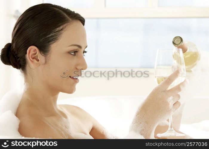 Close-up of a young woman pouring white wine into a wineglass