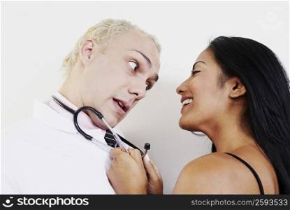 Close-up of a young woman pulling male doctor with a stethoscope