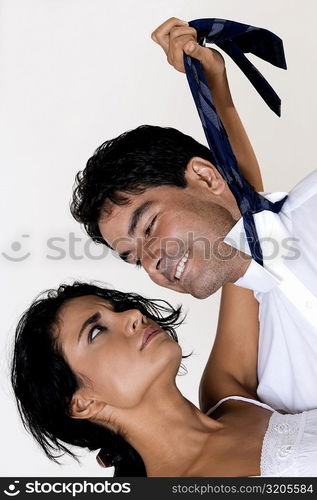 Close-up of a young woman pulling the tie of a mid adult man