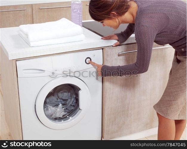 Close up of a young woman putting a cloth into washing machine