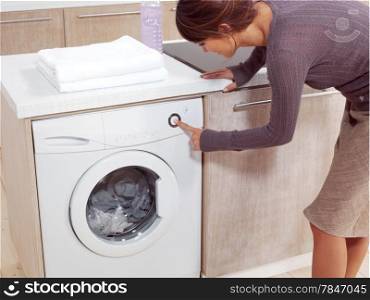 Close up of a young woman putting a cloth into washing machine