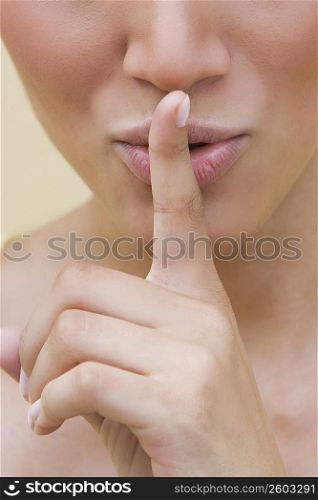 Close-up of a young woman putting her finger on her lips