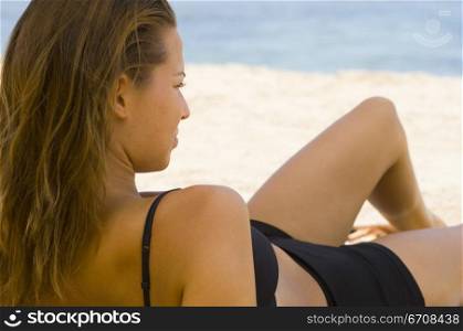 Close-up of a young woman reclining on the beach