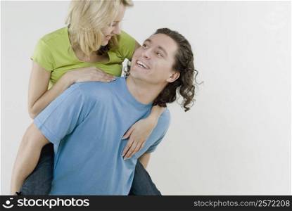Close-up of a young woman riding piggyback on a young man