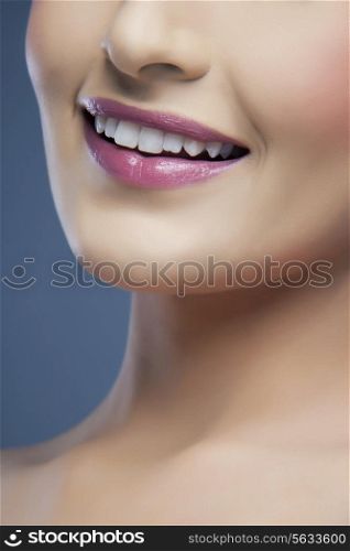 Close-up of a young woman&rsquo;s beautiful smile over colored background