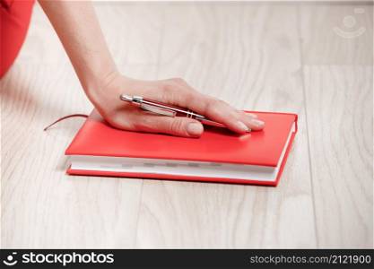 Close-up of a young woman&rsquo;s hand with a pen and notebook for writing plan of the day. The concept of working and studying at home. Close-up of a young woman&rsquo;s hand with a pen and notebook for writing plan of the day. The concept of working and studying at home.