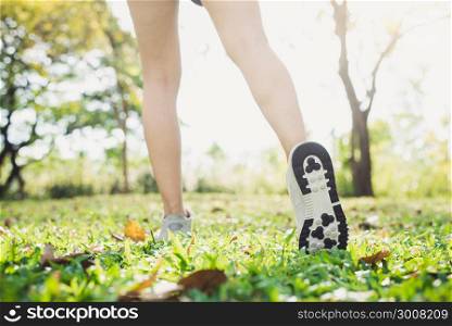 Close up of a young woman&rsquo;s legs in warming up the body by stretching her legs before morning excercise and yoga on the grass beneath warm light shining. Outdoor excercise concept.